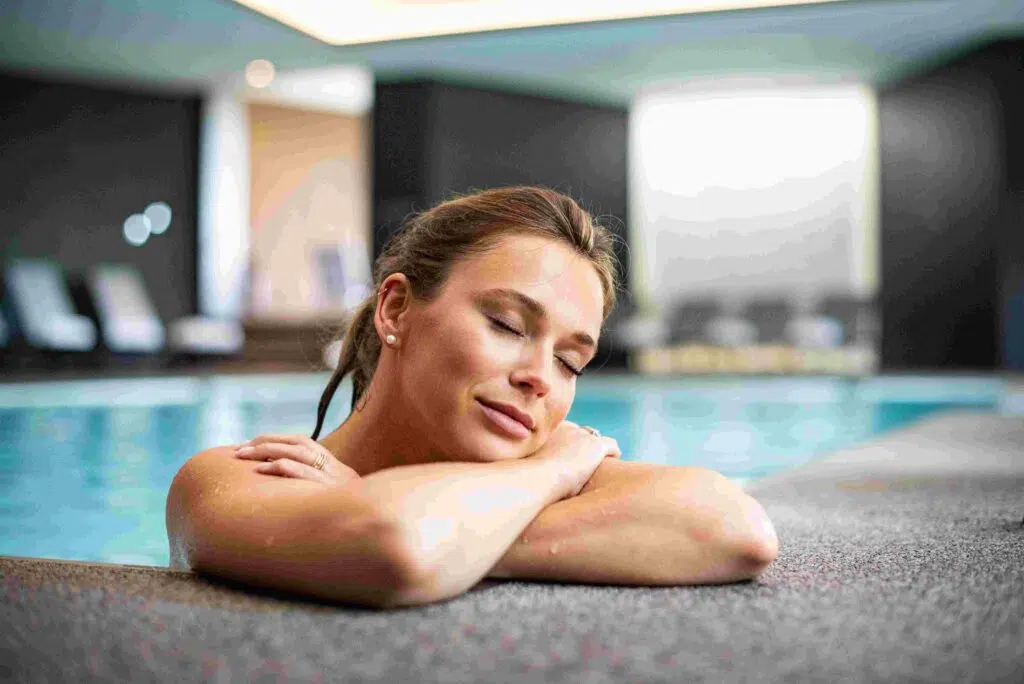 Femme Seule Relaxée Fermant Les Yeux Appuyé Contre Le Bord De La Piscine Du Centre Wellness Du Domaine Des Hautes Fagnes